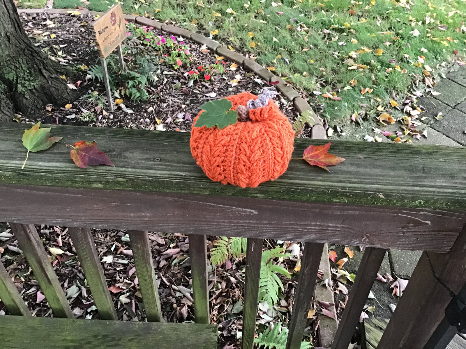 Small orange crocheted pumpkin with a green leaf and curly stem